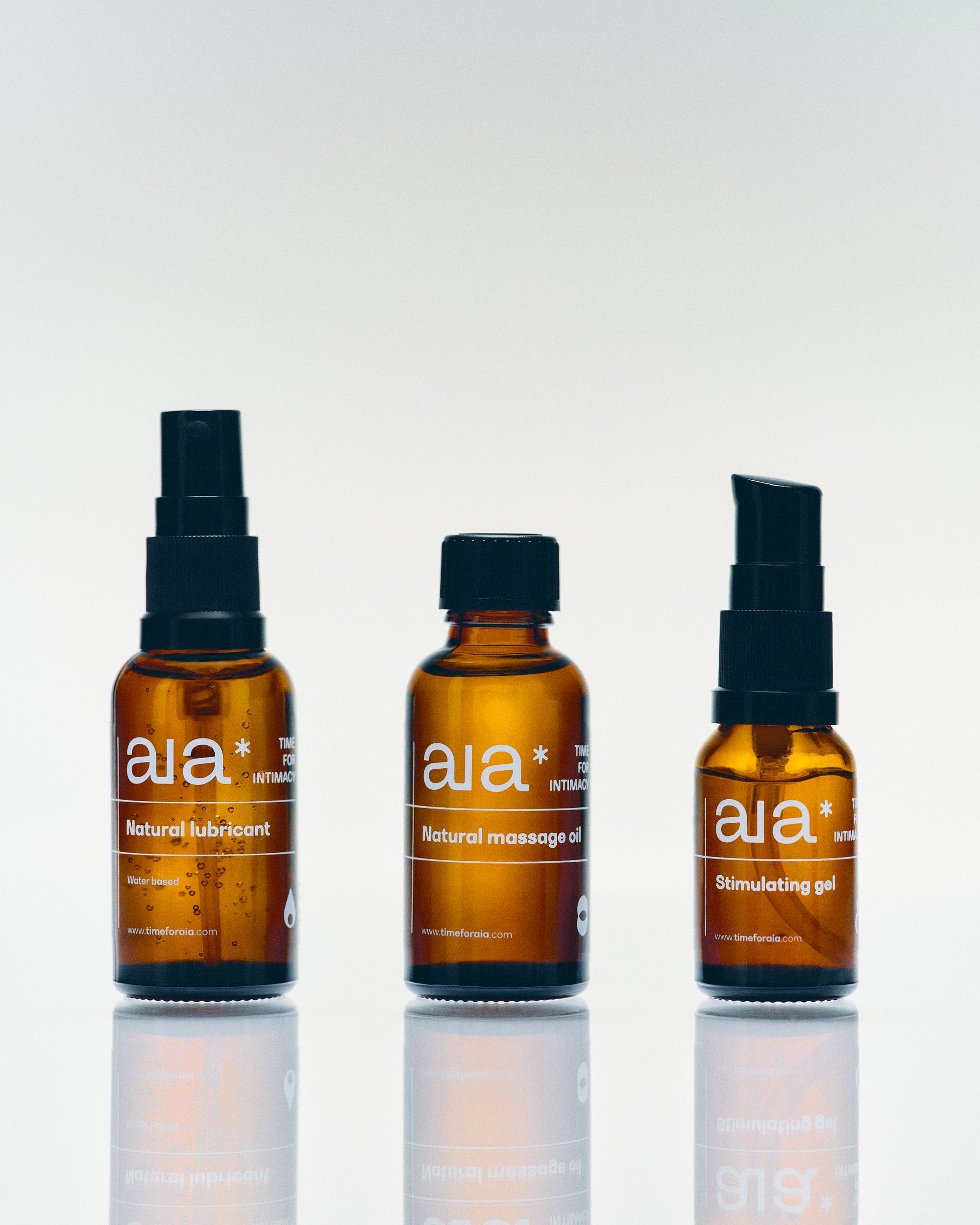 Aia Intimacy Box contents: amber glass bottles of natural lubricant, massage oil, and stimulating gel.